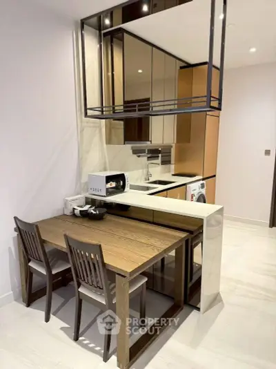 Modern kitchen with sleek design, featuring a compact dining area and integrated appliances.