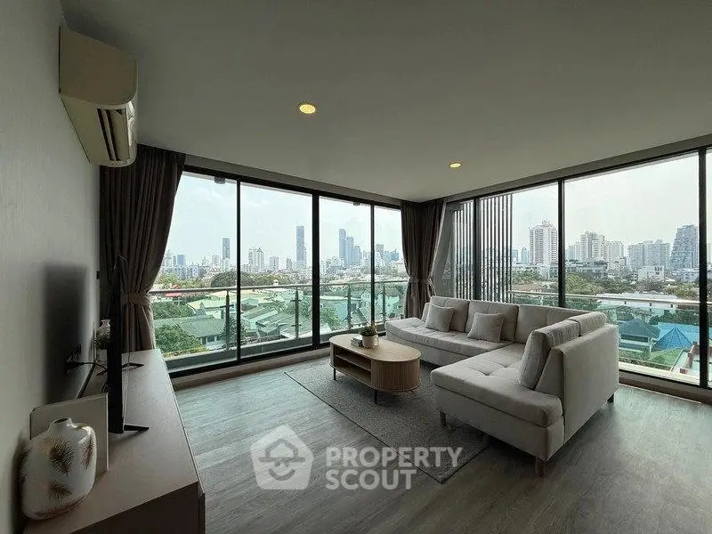 Spacious living room with panoramic city views and modern furnishings.