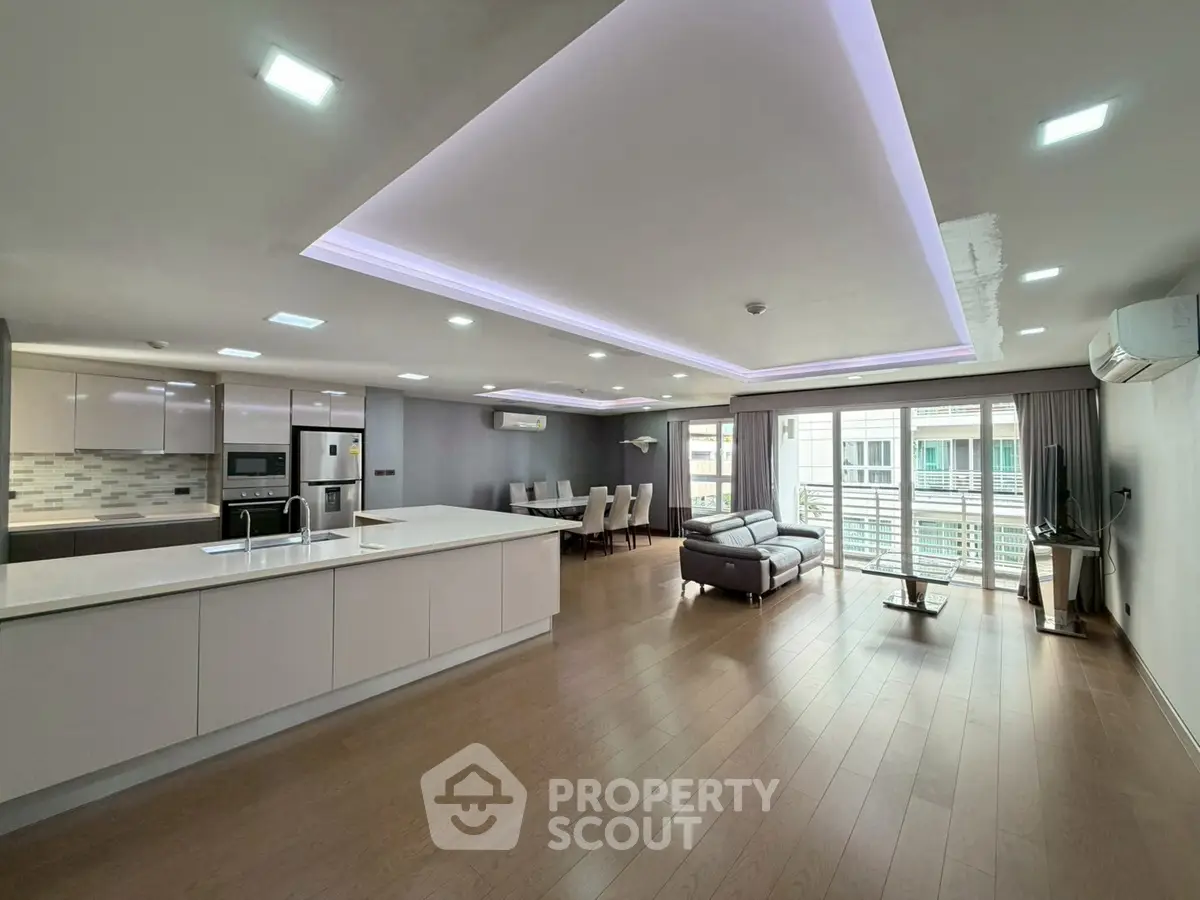 Spacious modern living room with open kitchen and balcony access