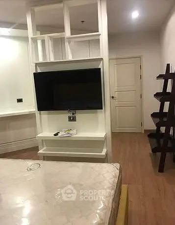 Modern bedroom with built-in TV and stylish shelving in a cozy apartment.