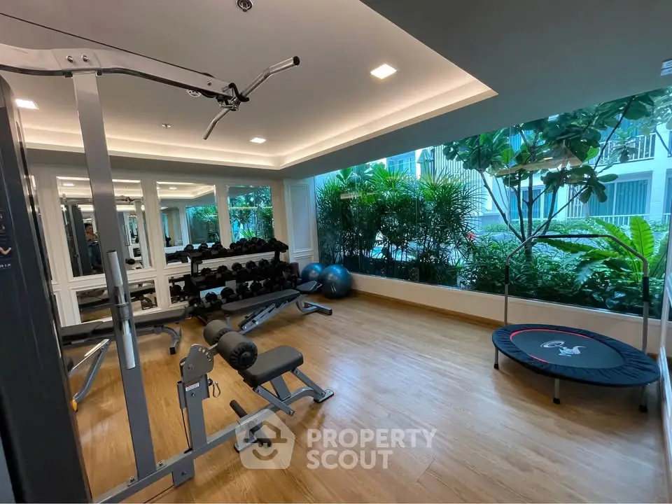 Modern gym with lush greenery view and state-of-the-art equipment in luxury residential building.