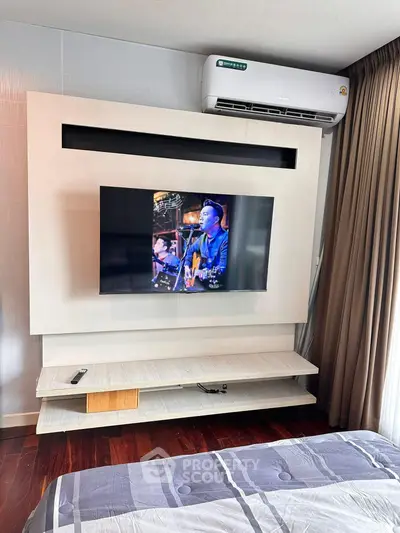 Modern bedroom with wall-mounted TV and air conditioning unit, featuring stylish decor and cozy ambiance.