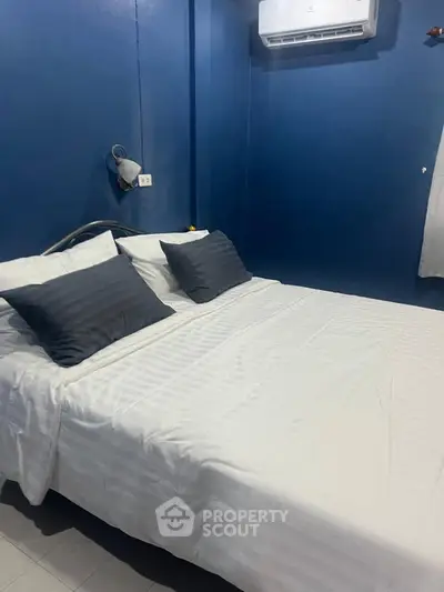 Cozy bedroom with blue walls and air conditioning, featuring a comfortable bed and modern lighting.