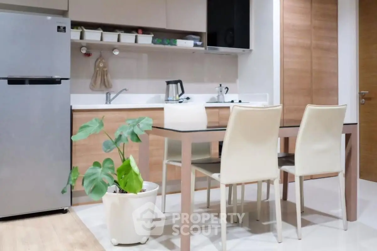 Modern kitchen with sleek design and dining area, featuring stainless steel fridge and stylish decor.