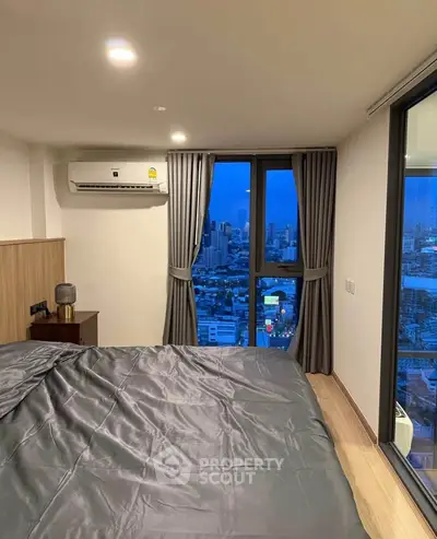 Modern bedroom with city view, featuring sleek design and large windows for natural light.