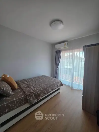 Cozy bedroom with modern decor and natural light from large window.