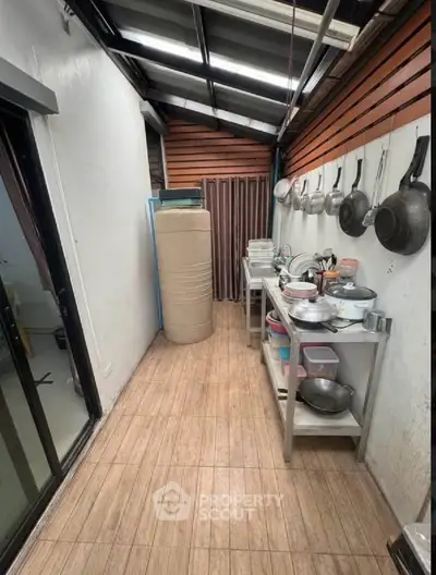 Compact kitchen with open layout and hanging pots, featuring a sleek design and efficient use of space.