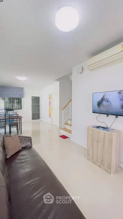 Spacious living room with modern decor and open layout, featuring a wall-mounted TV and sleek furniture.