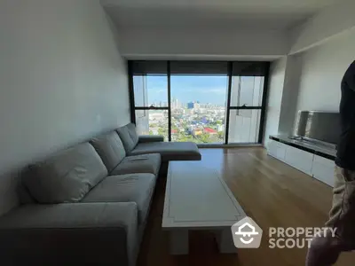 Spacious living room with modern furnishings and expansive city view through large windows, perfect for urban living.