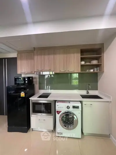 Modern kitchen with appliances including washing machine and microwave, sleek cabinetry and glossy floor.