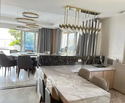 Luxurious open-layout kitchen and dining area with elegant marble finishes and modern lighting.