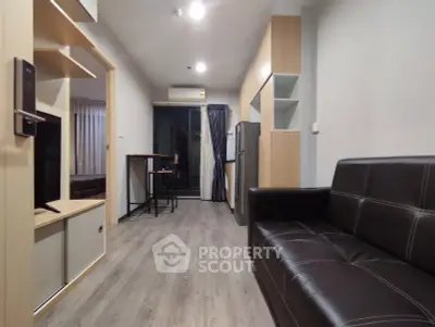 Modern living room with sleek leather sofa and open kitchen layout, featuring stylish wooden flooring and balcony access.