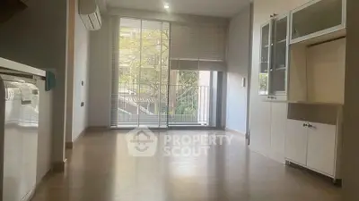 Spacious living room with large windows and built-in cabinets, perfect for modern living.