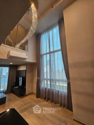 Luxurious high-ceiling living room with elegant chandelier and floor-to-ceiling windows.