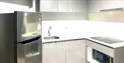 Modern kitchen with sleek appliances and minimalist design, featuring a fridge, microwave, and electric stove.
