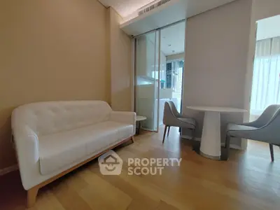 Modern living room with elegant white sofa and dining set, featuring wooden flooring and natural light.