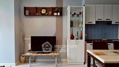 Modern living room with stylish decor and open kitchen layout, featuring sleek furniture and elegant shelving.