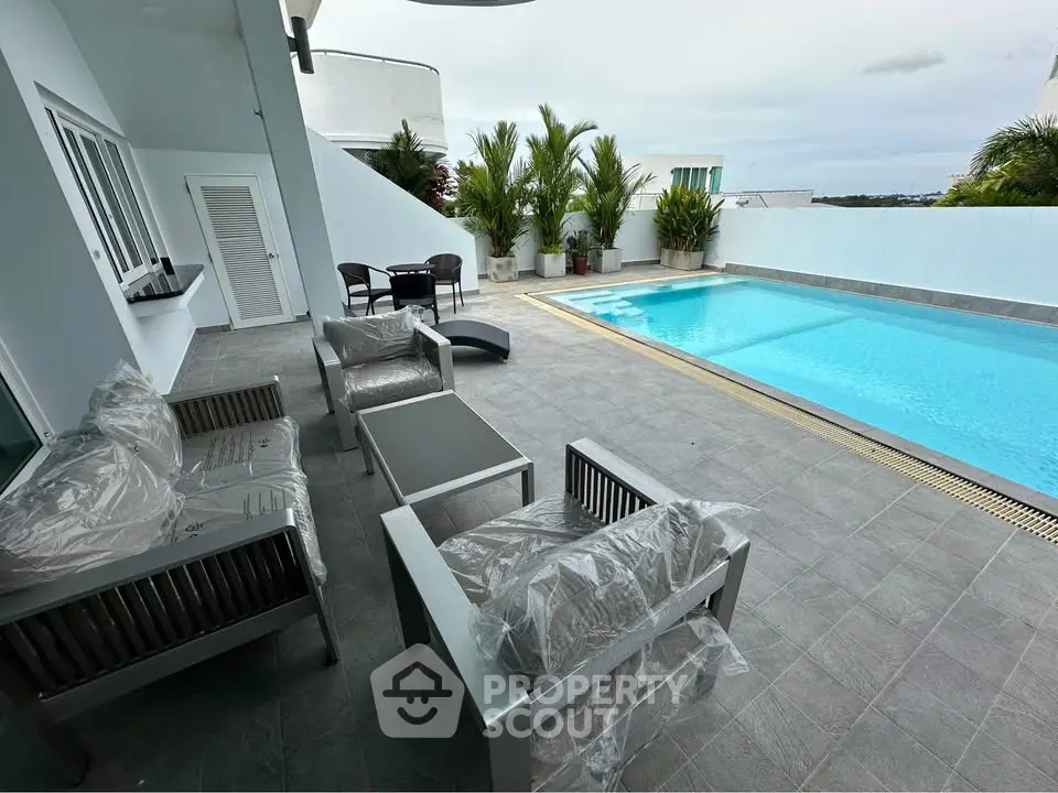 Luxurious private pool area with modern outdoor seating and lush greenery, perfect for relaxation and entertainment.