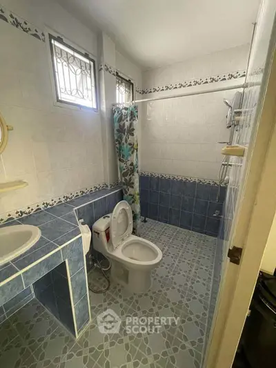 Spacious bathroom with blue tile accents and modern fixtures in a well-lit setting.
