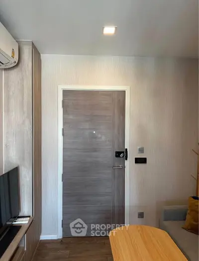 Modern living room with wooden door, air conditioning, and cozy seating area.