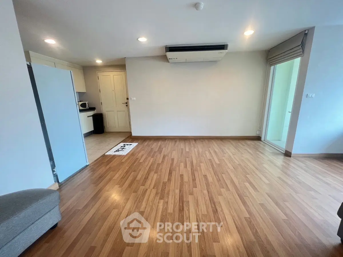 Spacious living room with wooden flooring and modern air conditioning unit