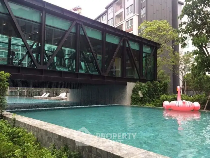 Luxurious condo pool with modern architecture and lush greenery