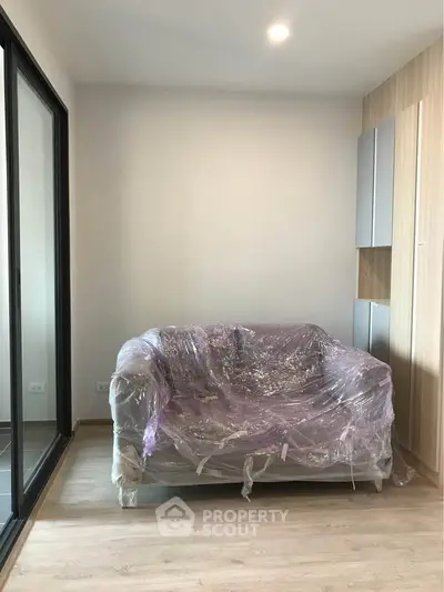 Modern living room with wrapped sofa and sliding glass doors to balcony