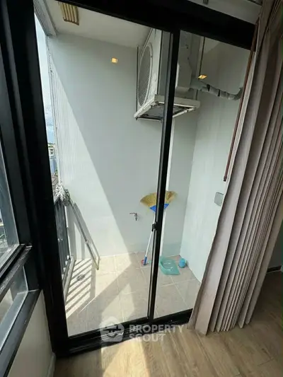 Compact balcony with sliding glass door and air conditioning unit, ideal for urban living.