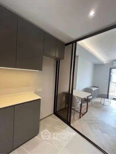 Modern kitchen with sleek cabinets and open layout leading to dining area