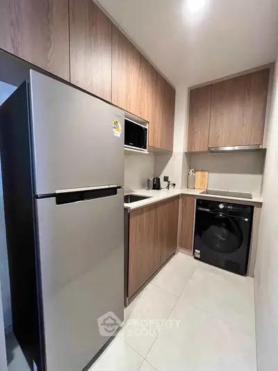 Modern kitchen with sleek appliances and wooden cabinetry in a compact layout.