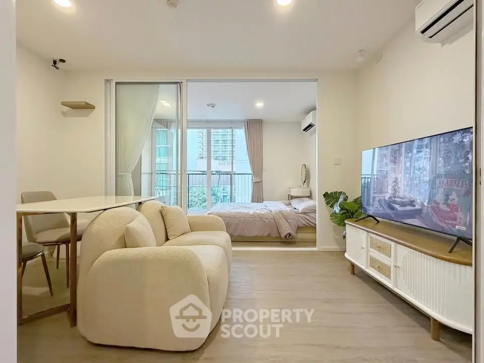 Modern open-plan living room with cozy seating and bedroom view, ideal for urban living.