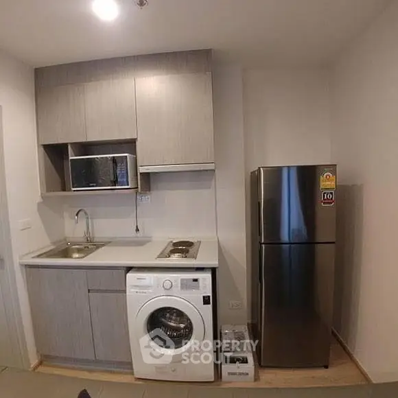 Compact modern kitchen with washing machine and stainless steel fridge