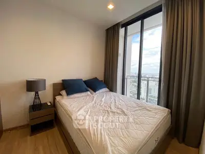 Modern bedroom with large window offering stunning city view, featuring cozy bed and stylish decor.
