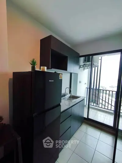 Modern kitchen with sleek black appliances and balcony view in urban apartment.
