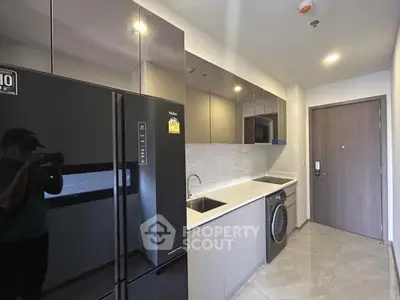 Modern kitchen with sleek appliances and washing machine in stylish apartment.