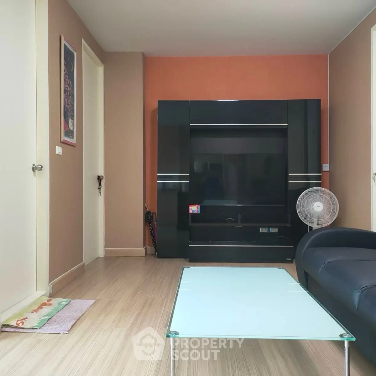Modern living room with sleek black entertainment center and glass coffee table.
