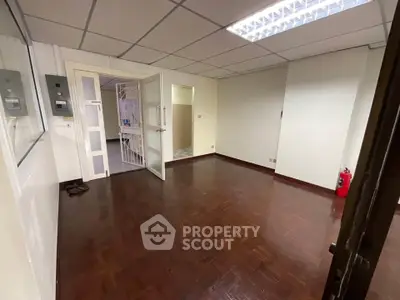 Spacious office room with wooden flooring and glass doors, ideal for professional workspace.