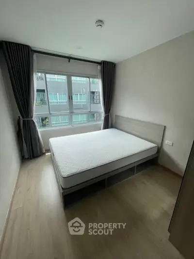 Modern bedroom with large window and minimalist design in urban apartment.