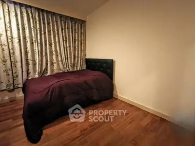 Cozy bedroom with wooden flooring and floral curtains, perfect for relaxation.