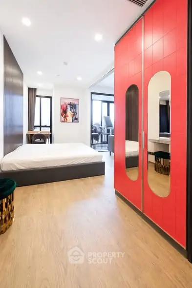 Modern bedroom with vibrant red wardrobe and sleek wooden flooring