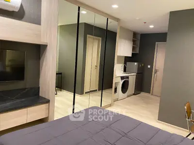 Modern bedroom with mirrored closet and in-unit laundry in stylish apartment.