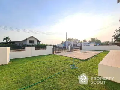 Spacious backyard with lush green lawn and modern fencing in serene neighborhood.