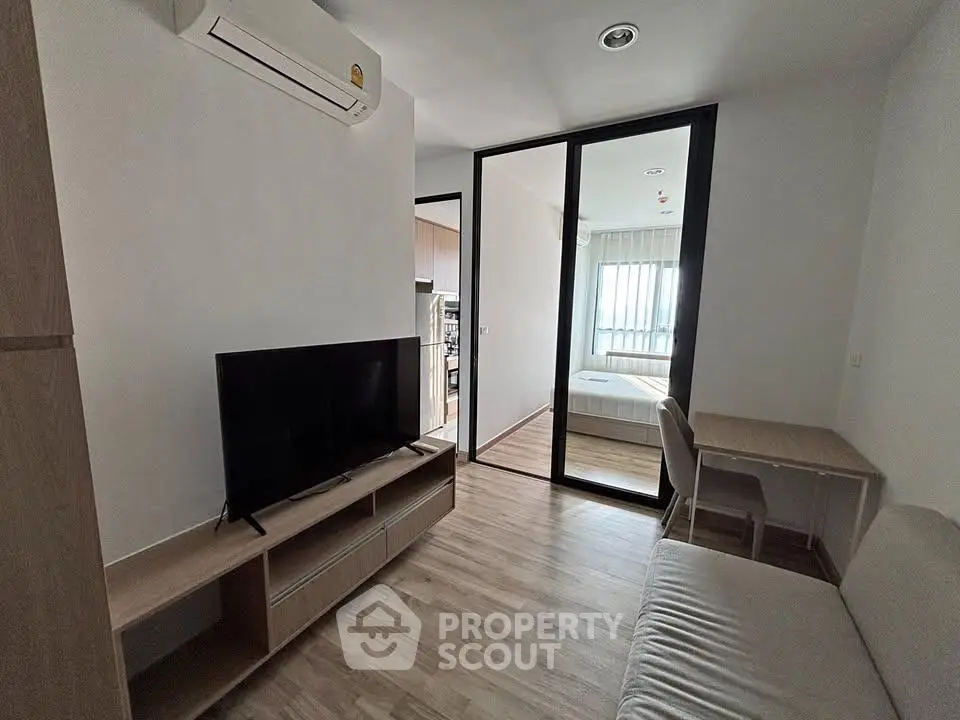 Modern apartment interior with living room and bedroom, featuring sleek furniture and natural light.