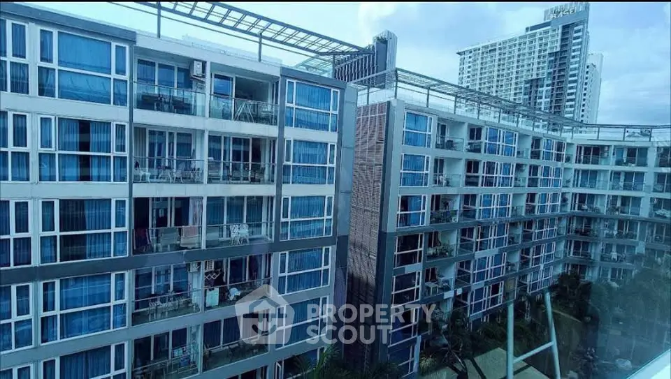 Modern apartment complex with glass balconies and urban skyline view.