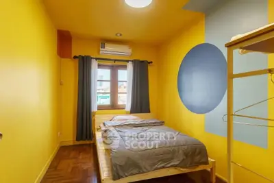 Cozy bedroom with vibrant yellow walls and modern decor, featuring a comfortable bed and natural light.