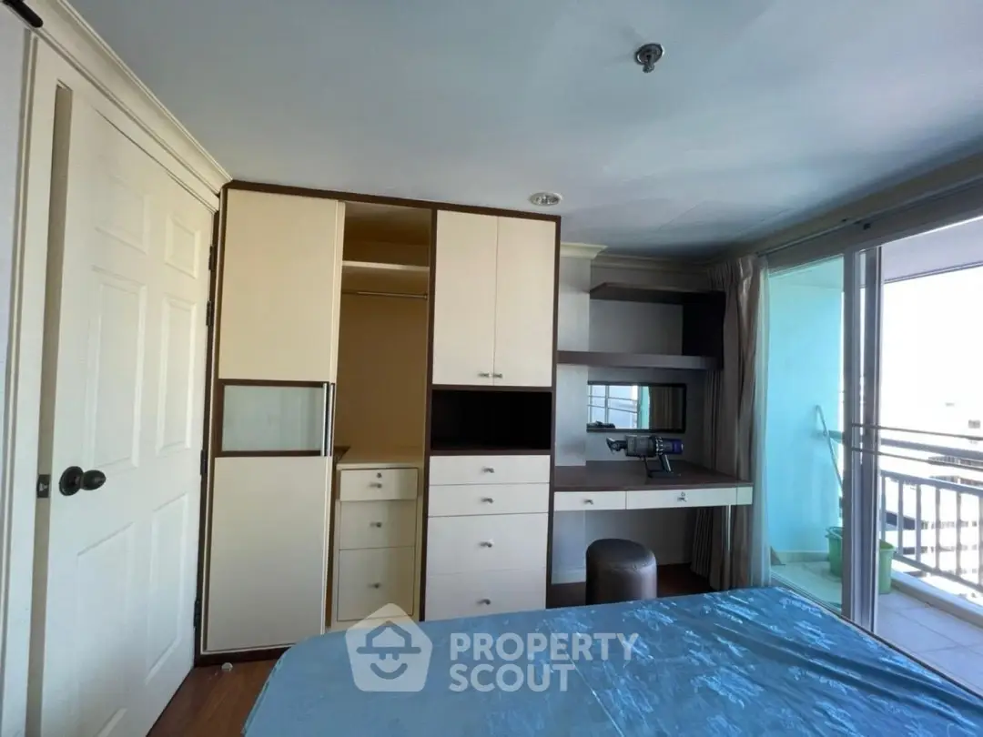 Spacious bedroom with built-in storage and balcony access in modern apartment