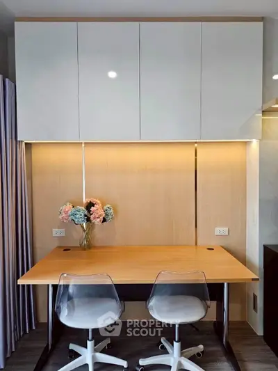 Modern study area with sleek desk, chairs, and floral decor in stylish apartment.