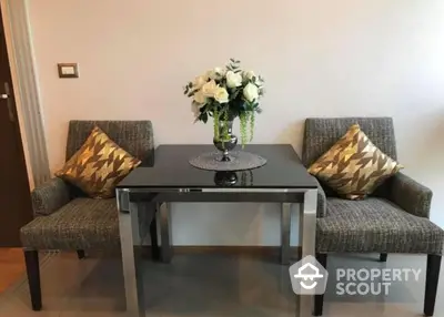 Elegant living space with modern grey sofas, patterned cushions, and a sleek black coffee table, complemented by a chic floral centerpiece.