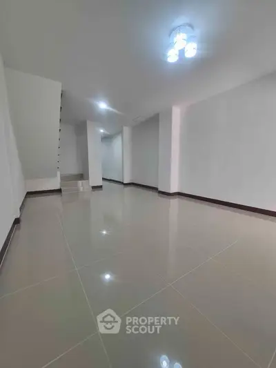Spacious modern interior with glossy tiled floors and minimalist lighting, perfect for versatile living space.