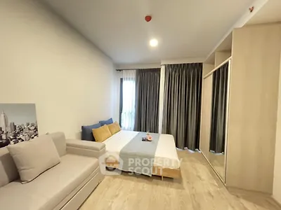Modern bedroom with cozy bed, stylish sofa, and large mirrored wardrobe in bright apartment.